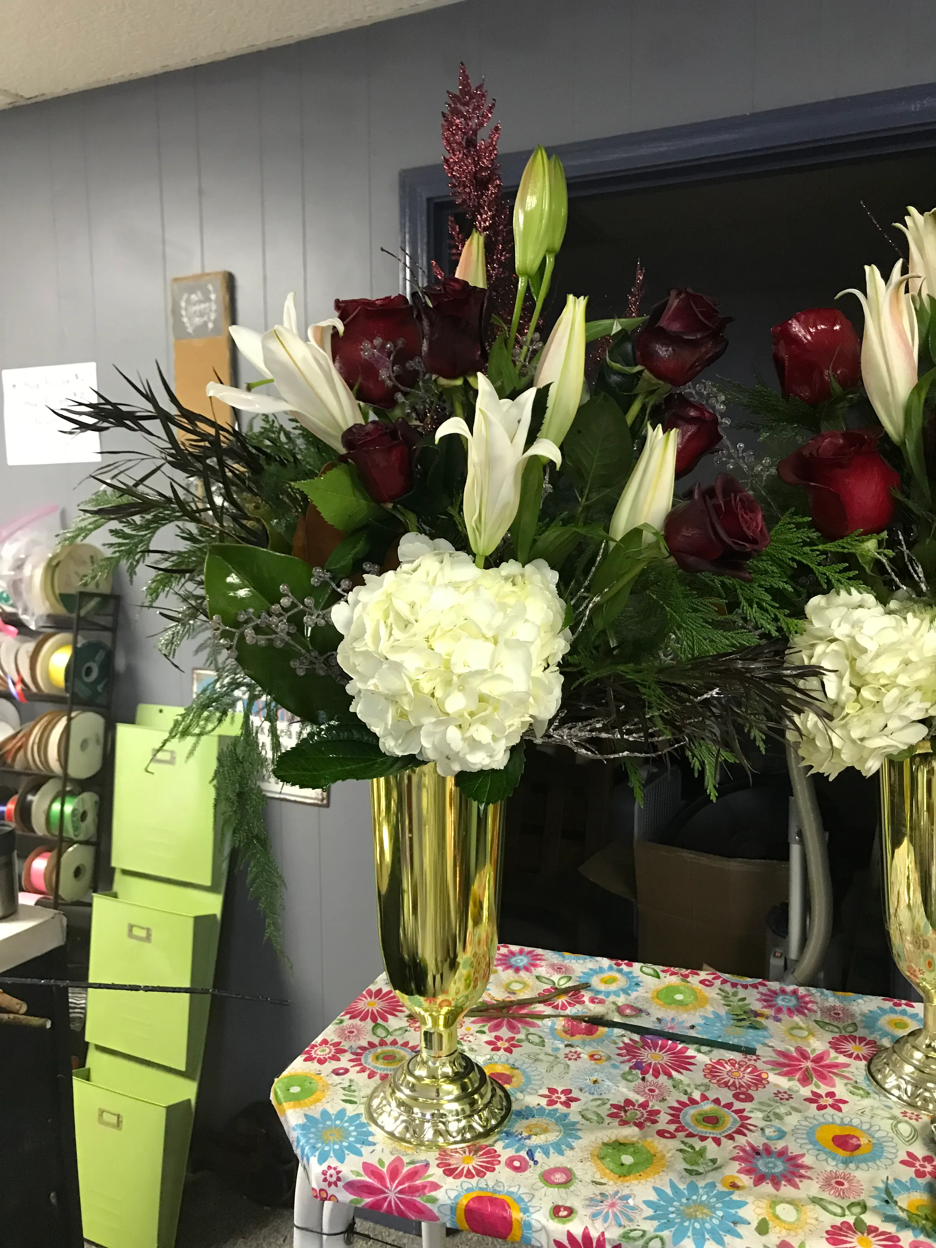 Burgundy roses, white lilies and hydrangea in gold urns