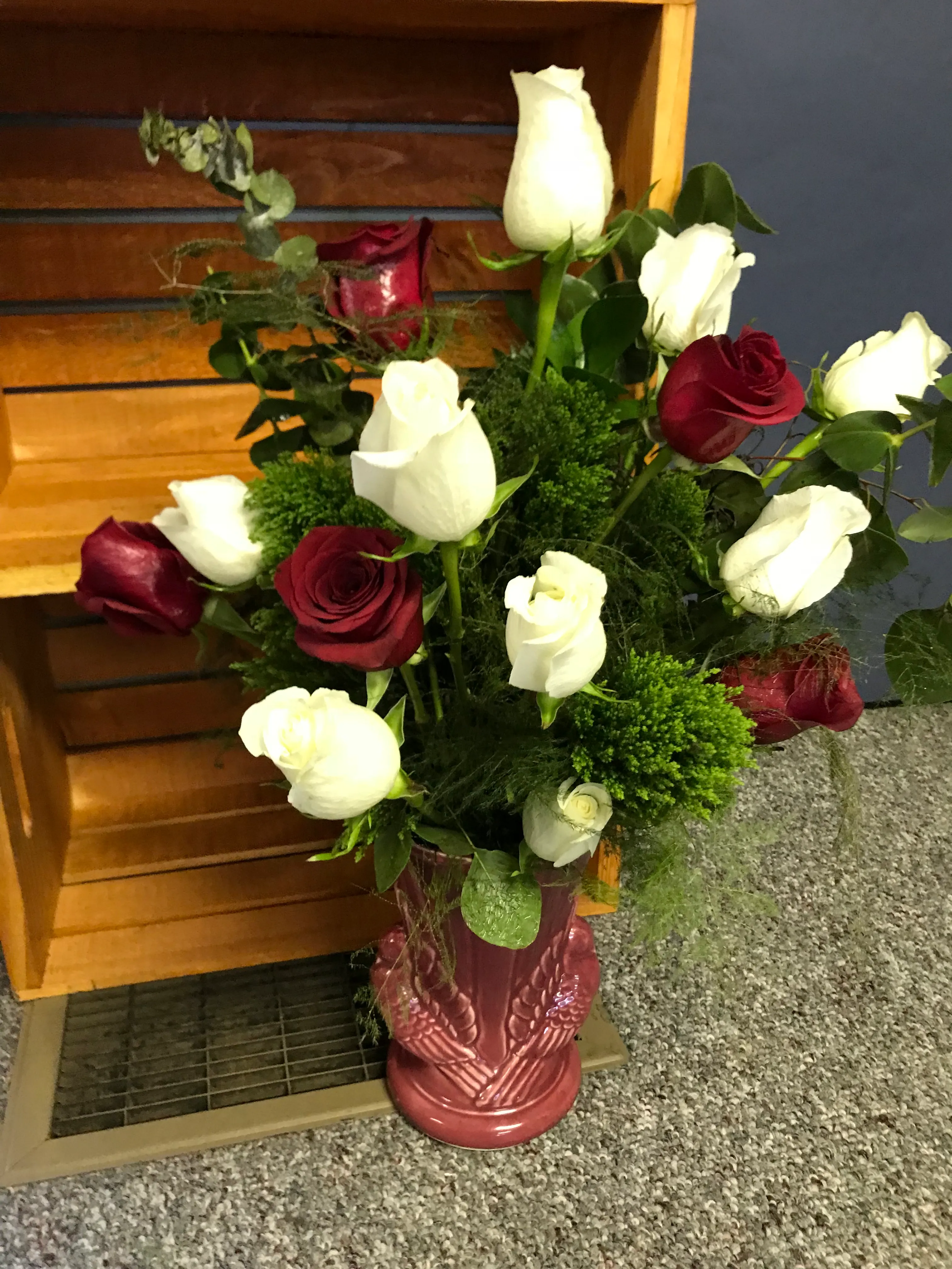 Roses in pottery vase against a wooden crate