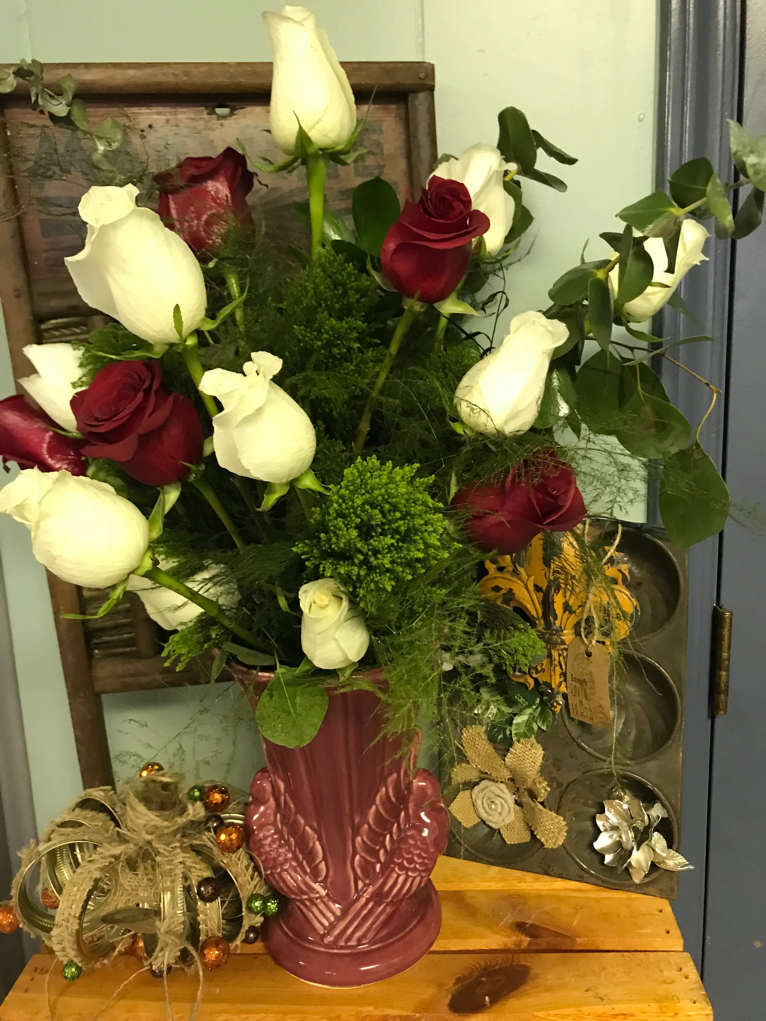 Red and white roses arranged in a dusty-pink pottery vase